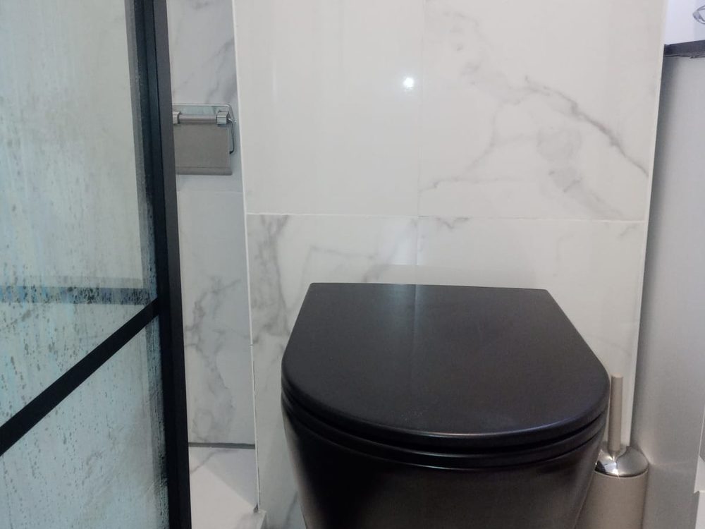 Toilette design avec WC suspendu noir et paroi de douche vitrée